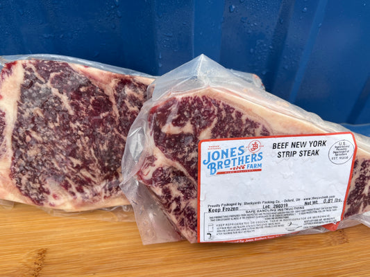 Packaged beef New York strip steak with Jones & Brothers label on a wooden surface.